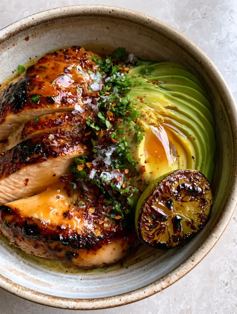 Honey Lime Chicken and Avocado Recipe: A Sticky, Citrus-Glazed Masterpiece 1 A rustic bowl featuring fanned avocado slices and pan-seared honey lime chicken with cilantro garnish.