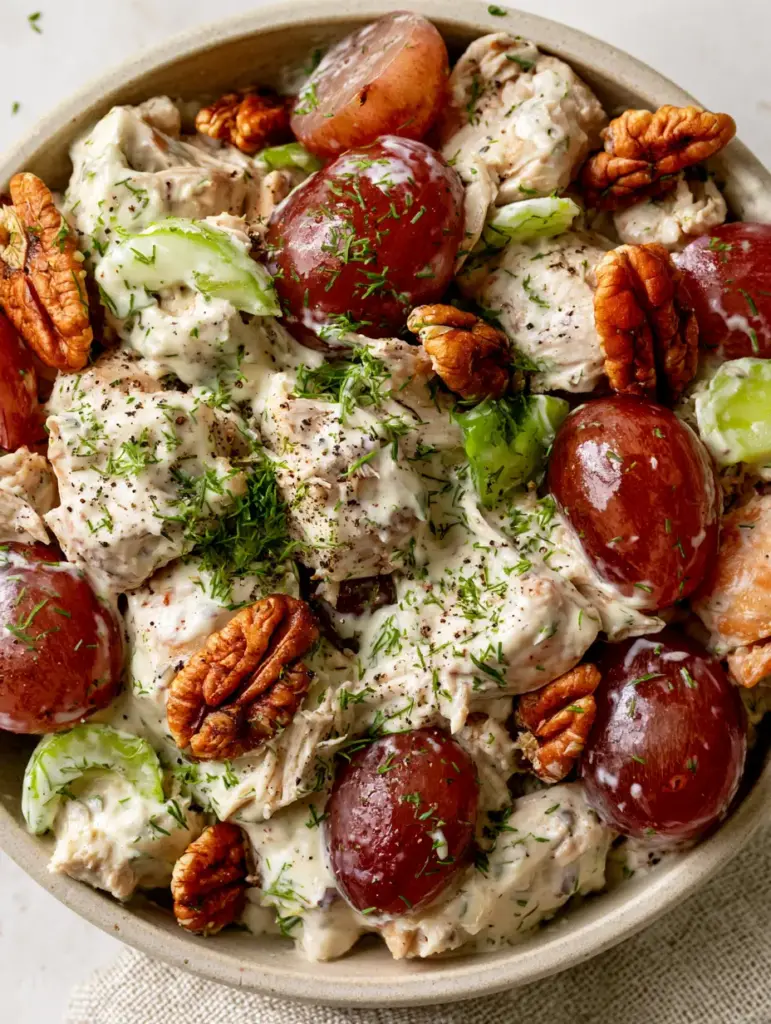 Chicken Salad with Grapes: The Ultimate Creamy and Crunchy Hand-Pulled Recipe 1 Close up of golden-brown pecans and glistening halved red grapes in a creamy chicken salad with grapes.